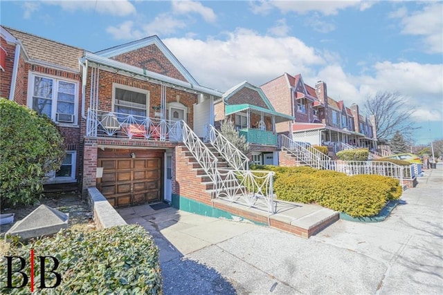 view of front of house featuring brick siding, stairway, driveway, and a garage