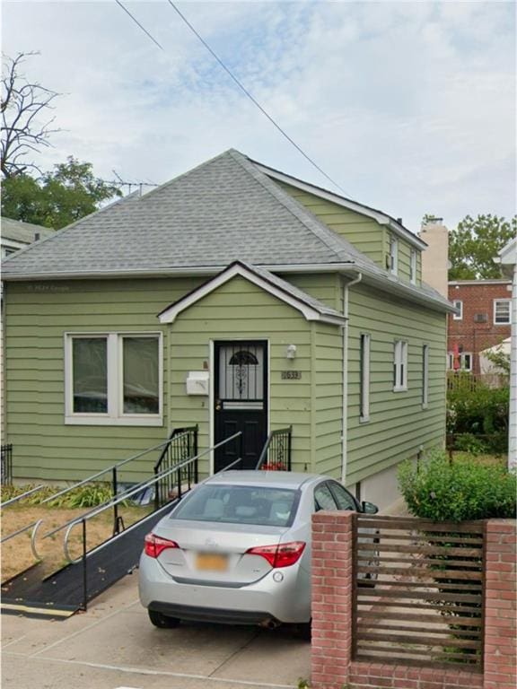 bungalow-style home with roof with shingles and fence