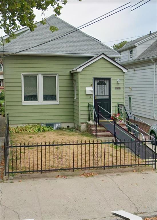 view of front facade with a fenced front yard, entry steps, and roof with shingles