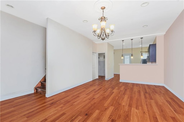 unfurnished living room with baseboards, an inviting chandelier, stairs, light wood-type flooring, and recessed lighting