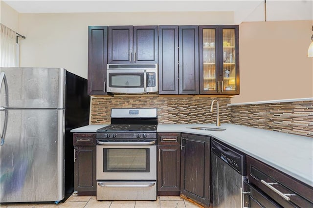 kitchen featuring a sink, light countertops, stainless steel appliances, and glass insert cabinets