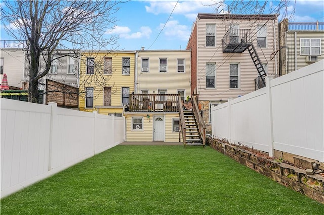 rear view of property with a fenced backyard, a lawn, stairs, and a deck