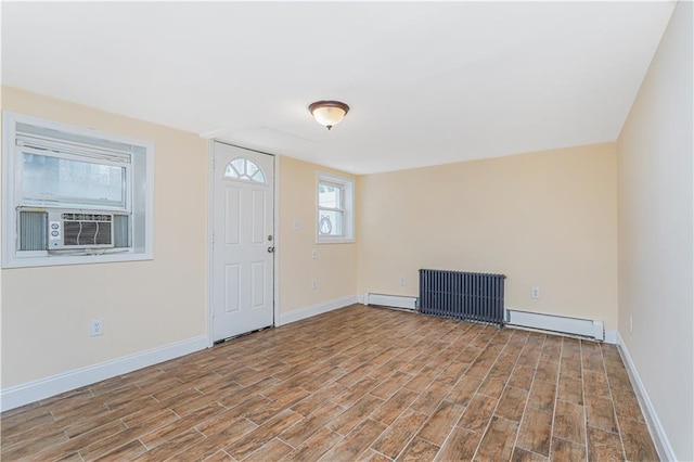 spare room with baseboards, a baseboard radiator, light wood-style flooring, and radiator