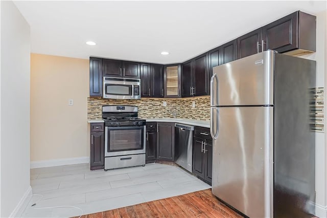 kitchen featuring glass insert cabinets, tasteful backsplash, appliances with stainless steel finishes, and light countertops