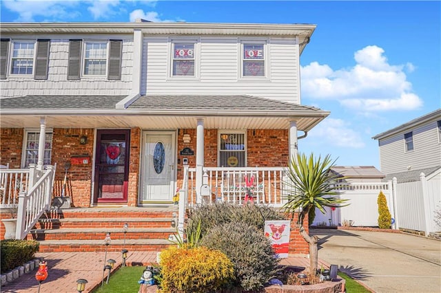 view of front of home featuring covered porch, driveway, brick siding, and a shingled roof