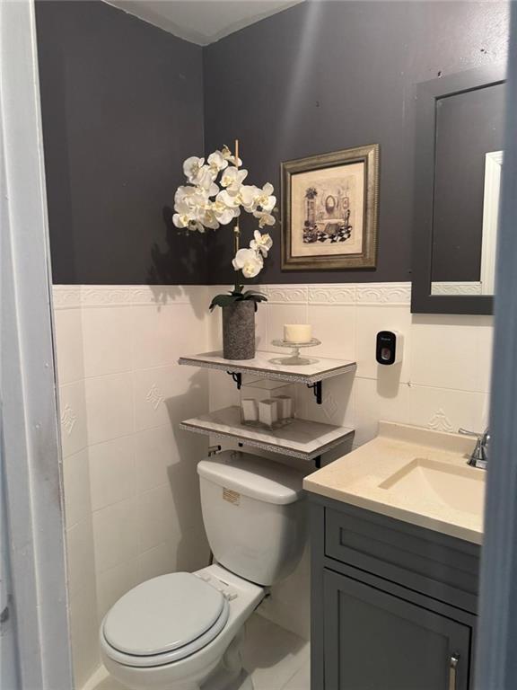 bathroom featuring tile walls, toilet, and vanity