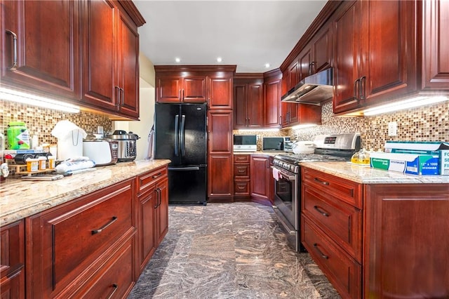 kitchen with freestanding refrigerator, dark brown cabinets, under cabinet range hood, stainless steel gas range oven, and tasteful backsplash