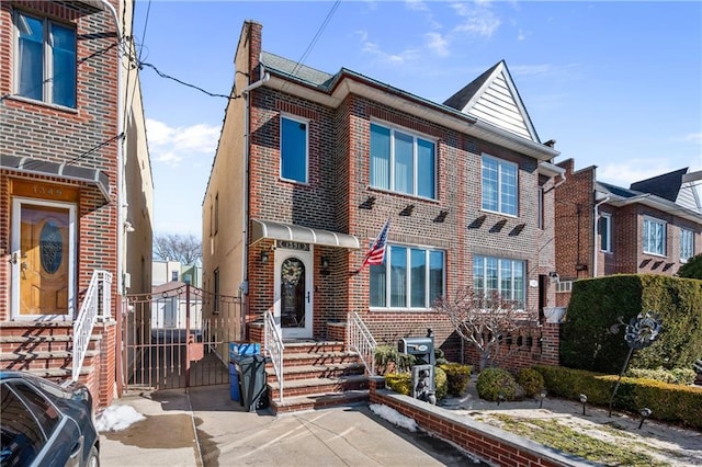 townhome / multi-family property featuring a gate and brick siding