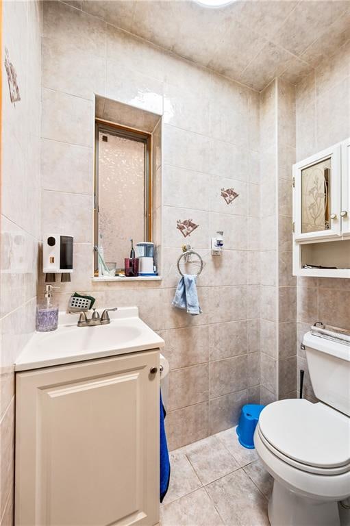 bathroom featuring tile patterned floors, toilet, tile walls, and vanity