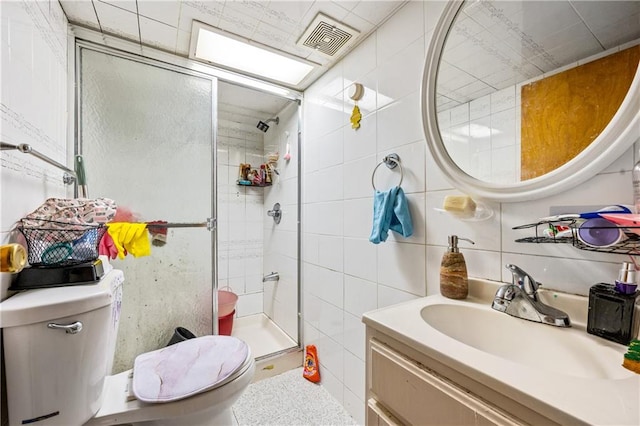 full bathroom with visible vents, toilet, a stall shower, tile walls, and vanity