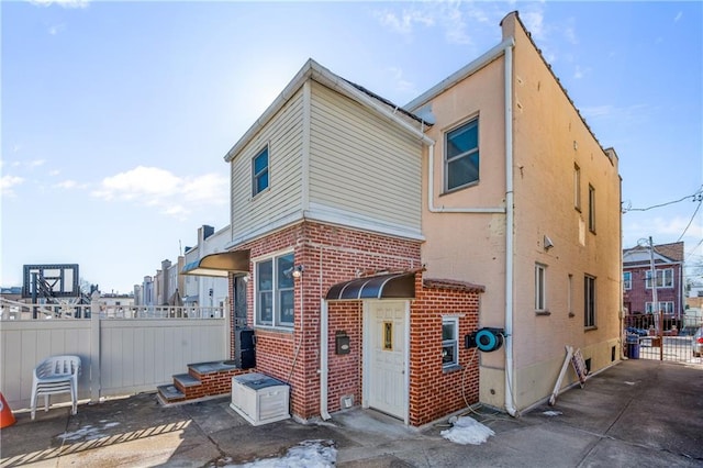 back of house featuring a patio area, brick siding, and fence