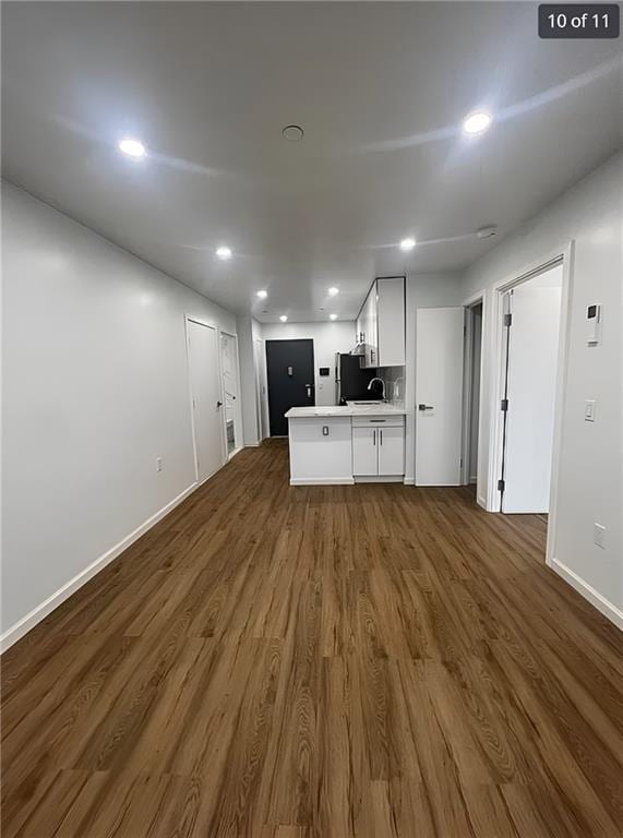 interior space with dark wood-type flooring, white cabinetry, baseboards, open floor plan, and light countertops