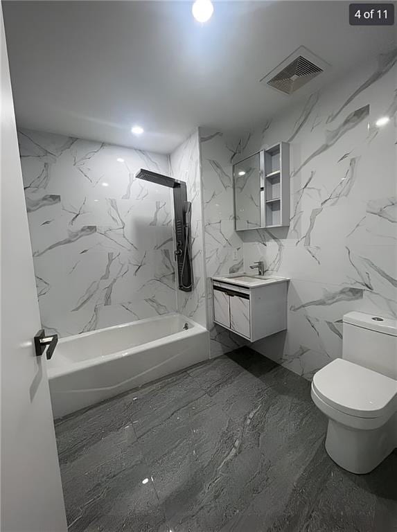 bathroom featuring toilet, tub / shower combination, vanity, and marble finish flooring