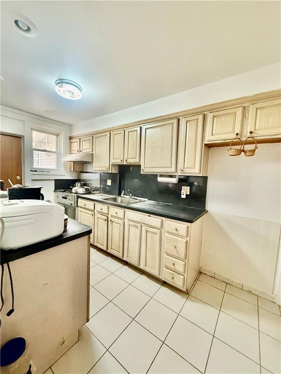 kitchen featuring tasteful backsplash, light tile patterned floors, stainless steel stove, and light brown cabinets