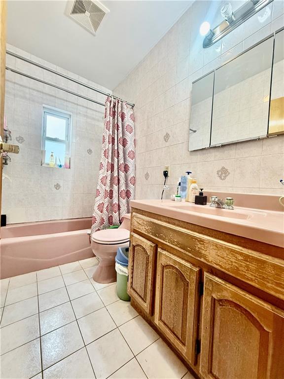 bathroom featuring shower / tub combo with curtain, tile walls, toilet, tile patterned flooring, and visible vents