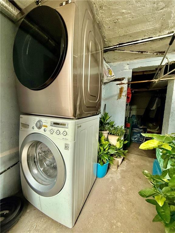clothes washing area featuring stacked washer / dryer and laundry area