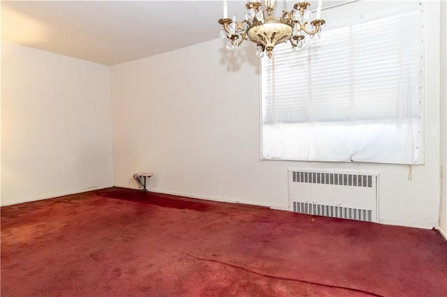 carpeted spare room with a chandelier and radiator heating unit