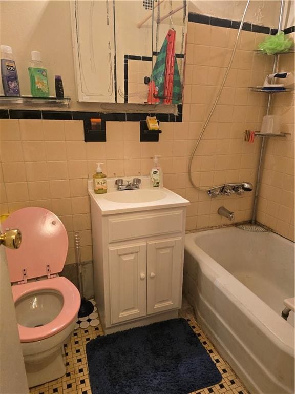 bathroom with toilet, tub / shower combination, vanity, and tile walls