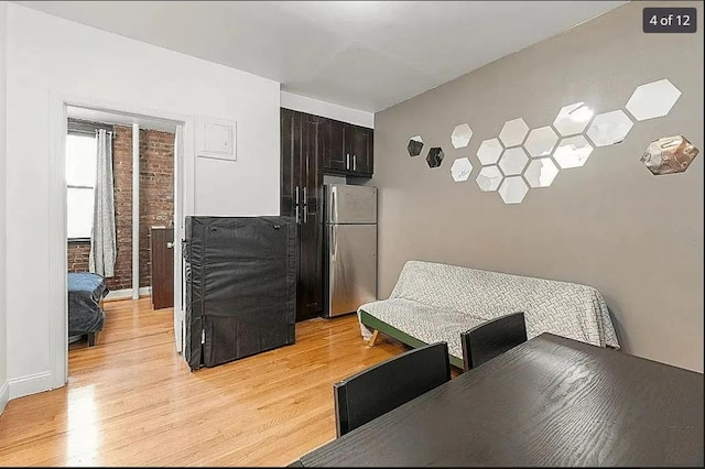 dining space with brick wall and light hardwood / wood-style flooring