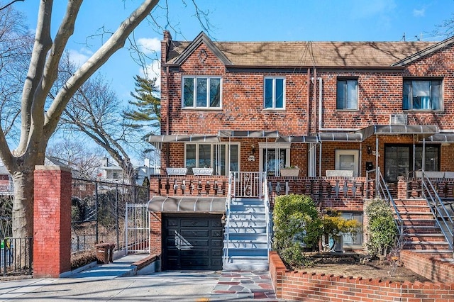 multi unit property featuring brick siding, stairway, an attached garage, and a porch