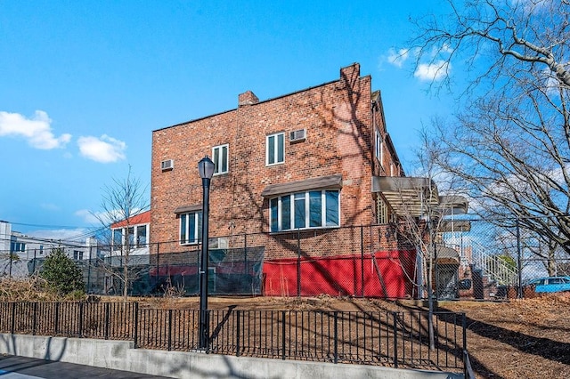 view of home's exterior featuring brick siding, a chimney, stairs, and fence