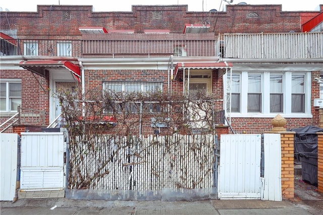 view of front of property with brick siding and a balcony