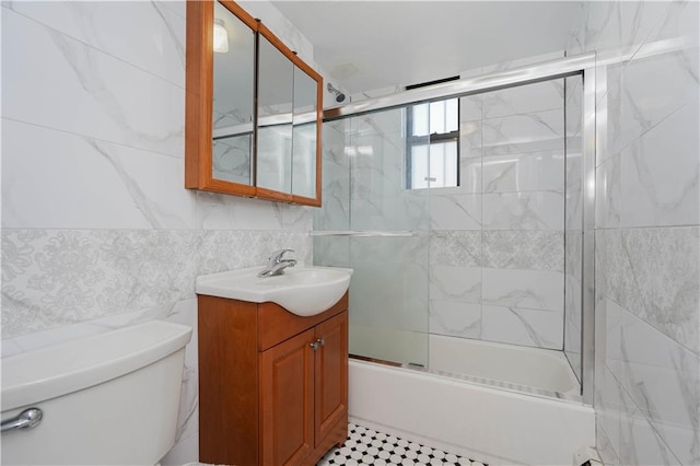 full bathroom featuring vanity, tile walls, shower / bath combination with glass door, and toilet