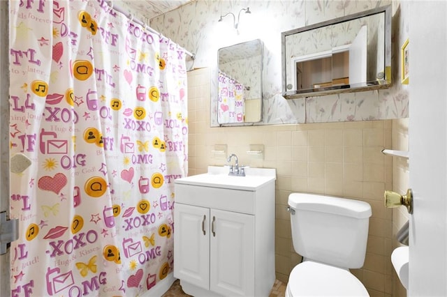 bathroom with vanity, tile walls, toilet, and walk in shower