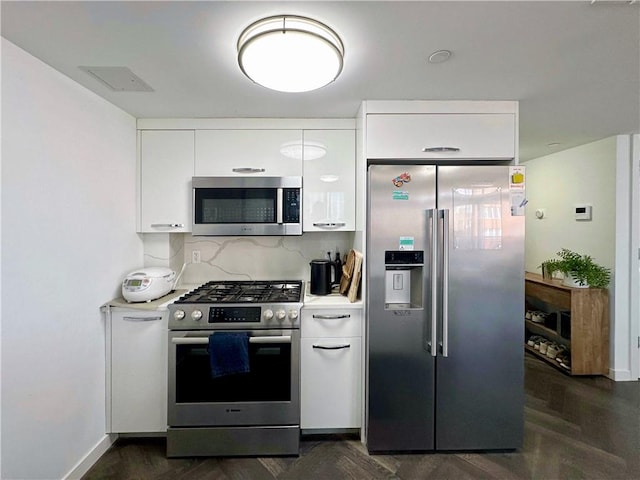 kitchen featuring appliances with stainless steel finishes, light countertops, white cabinetry, and backsplash