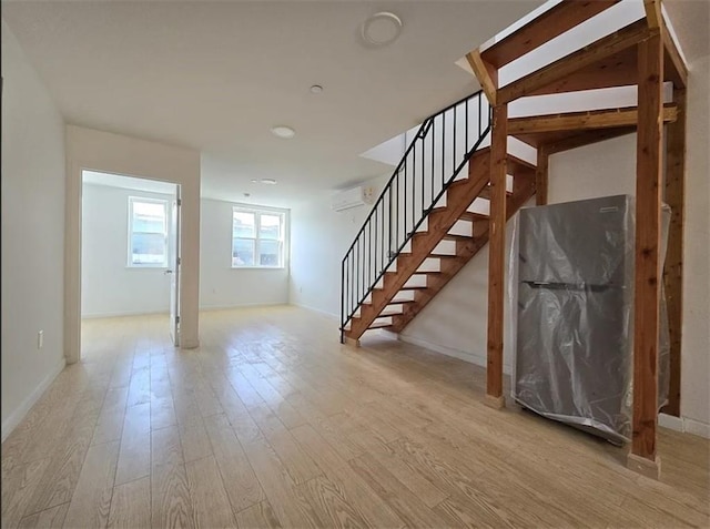 basement with an AC wall unit and light hardwood / wood-style floors