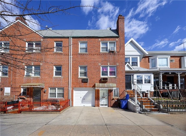 view of front of house featuring an attached garage, brick siding, driveway, and a chimney