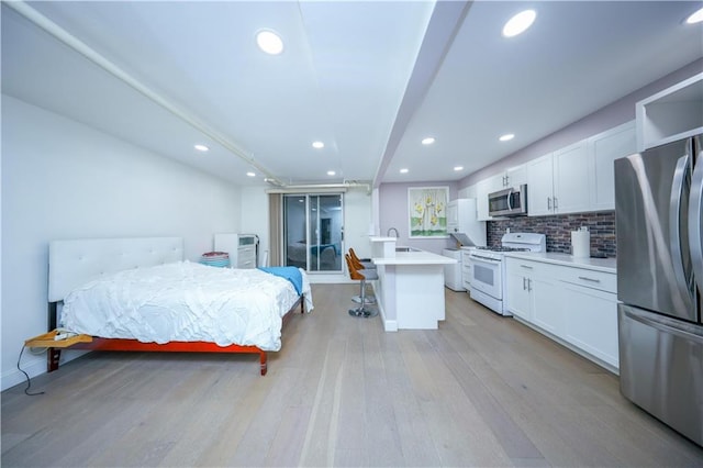 bedroom with light wood-style flooring, recessed lighting, freestanding refrigerator, and a sink