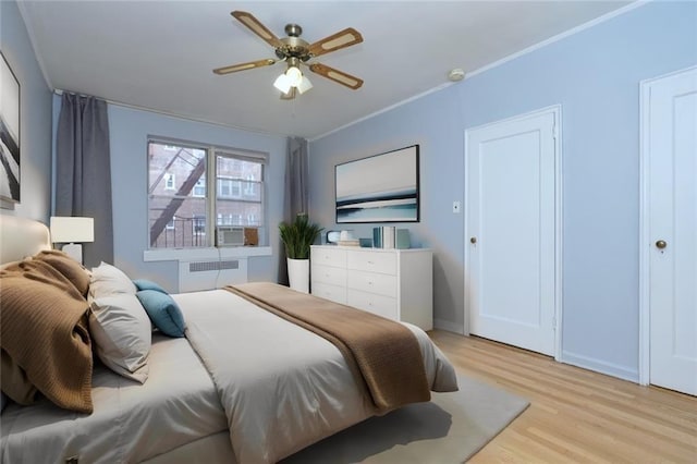 bedroom with radiator, ceiling fan, baseboards, and light wood-type flooring