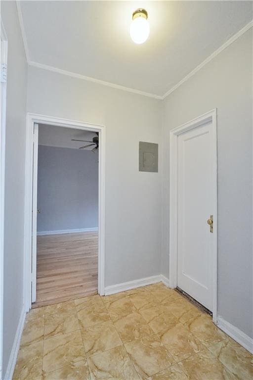 empty room featuring electric panel, baseboards, and crown molding