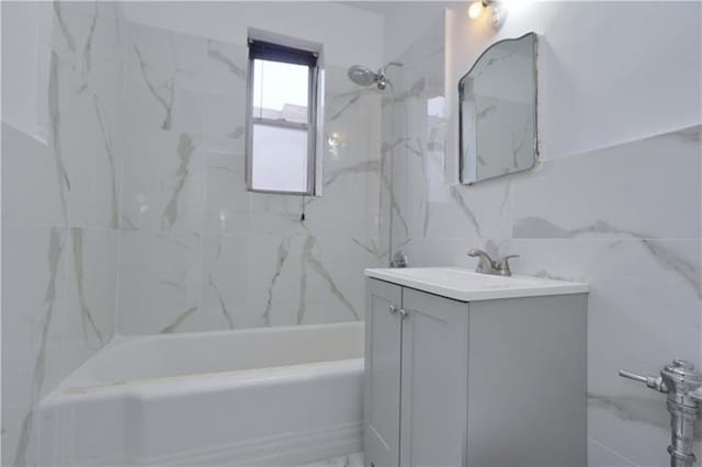 full bath with vanity, tub / shower combination, and tile walls