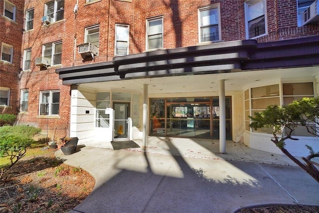 view of exterior entry with cooling unit, brick siding, and driveway