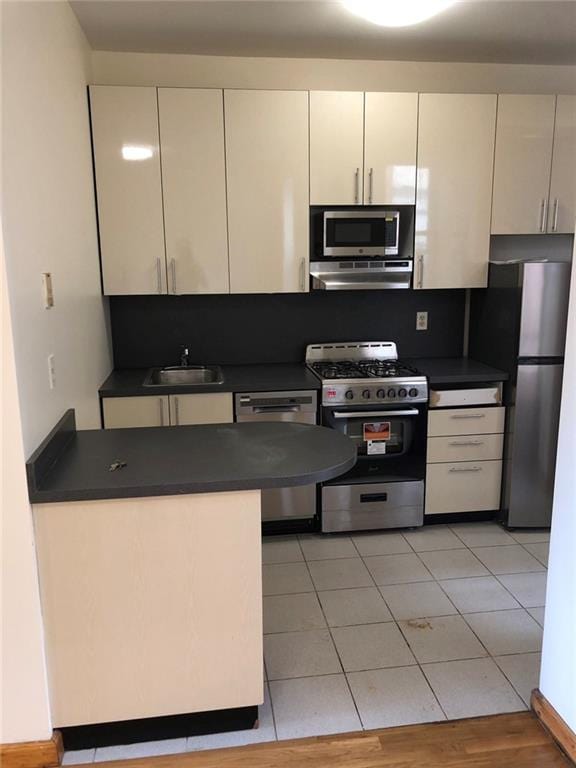 kitchen with white cabinets, light tile patterned floors, stainless steel appliances, and sink