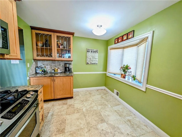 kitchen with stone counters, appliances with stainless steel finishes, and backsplash