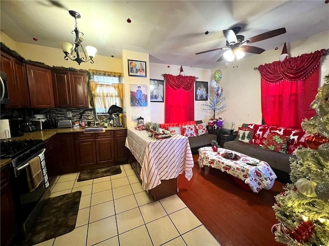 622 Ocean View Ave, Brooklyn, NY 11235 - kitchen featuring light tile patterned flooring, black range with gas stovetop, tasteful backsplash, ceiling fan with notable chandelier, and decorative light fixtures