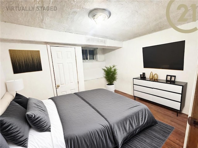 bedroom with dark wood-style floors, a textured ceiling, and visible vents