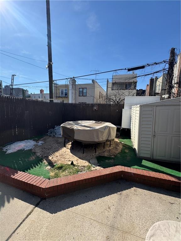 view of yard featuring an outbuilding, fence private yard, a storage shed, and a patio