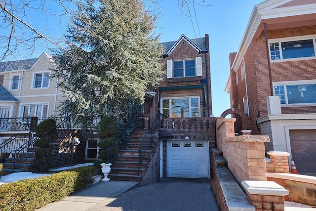 view of front of property featuring a garage, brick siding, driveway, and stairway