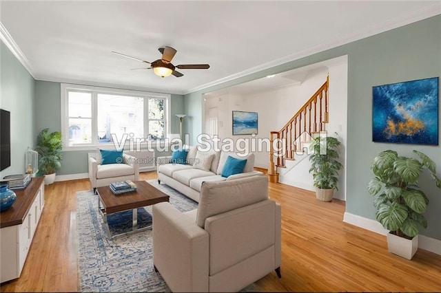 living area featuring a ceiling fan, baseboards, ornamental molding, stairs, and light wood-type flooring