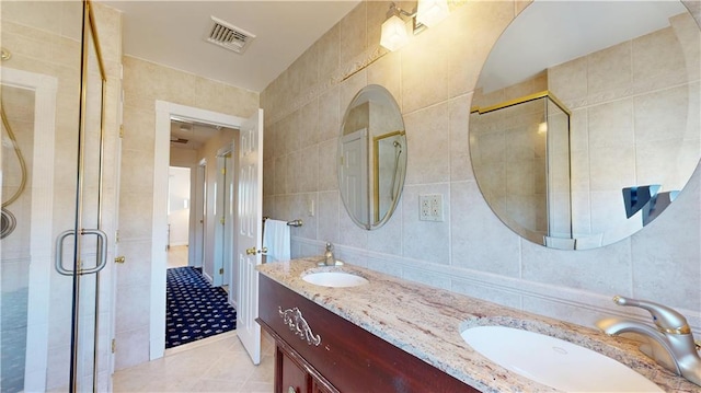 bathroom featuring tile patterned floors, tile walls, a shower with shower door, and vanity