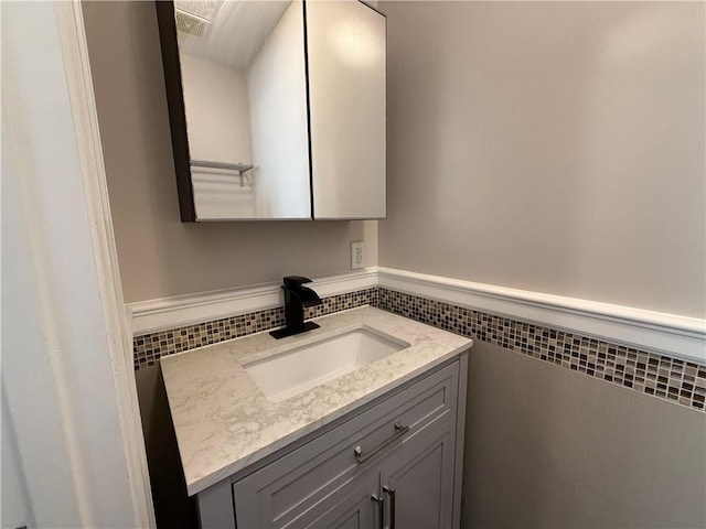 bathroom featuring wainscoting, vanity, and tile walls