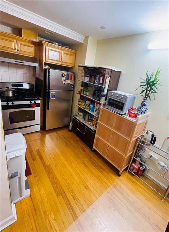 kitchen featuring decorative backsplash, light wood-type flooring, and stainless steel appliances