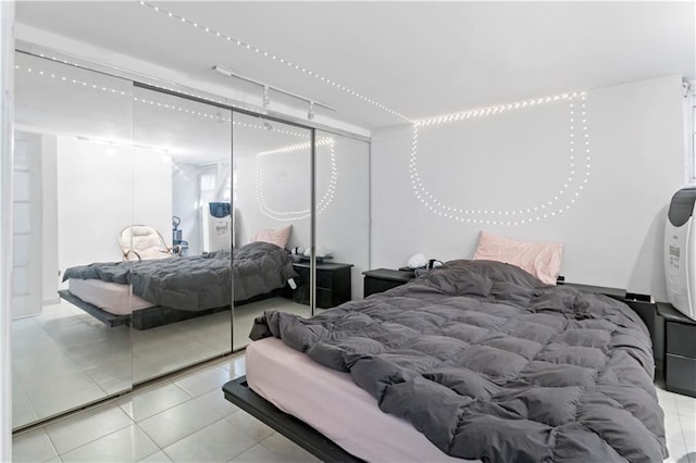 bedroom with light tile patterned floors, rail lighting, and a closet