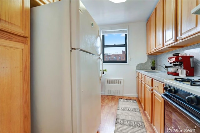 kitchen featuring visible vents, gas range, freestanding refrigerator, light countertops, and backsplash