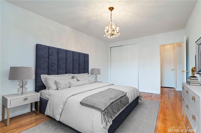 bedroom with light wood-style floors, a closet, and an inviting chandelier