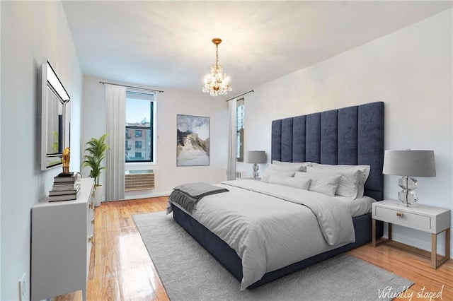 bedroom featuring light wood-style floors, a wall mounted AC, and an inviting chandelier